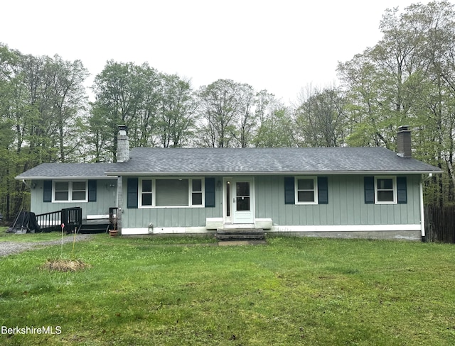view of front facade with covered porch, roof with shingles, a chimney, and a front lawn