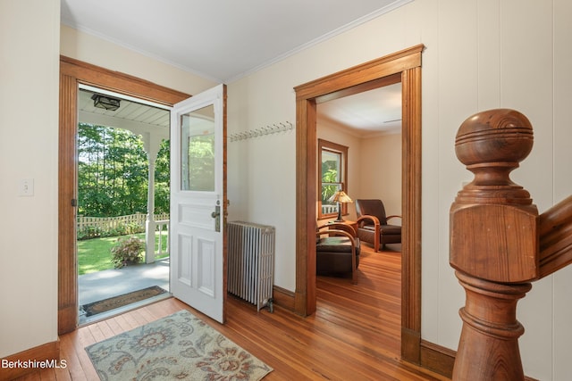 entryway with crown molding, radiator heating unit, and hardwood / wood-style floors