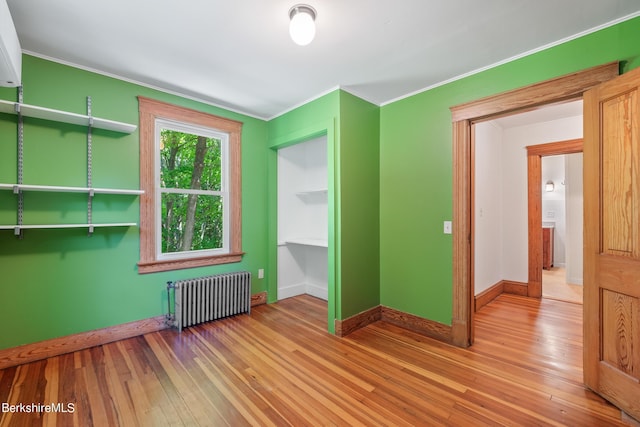 unfurnished room featuring light wood-type flooring, ornamental molding, and radiator