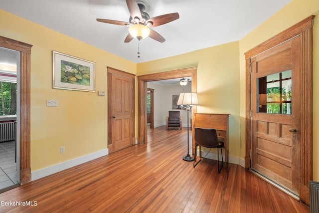 interior space with a wealth of natural light, hardwood / wood-style floors, and radiator heating unit