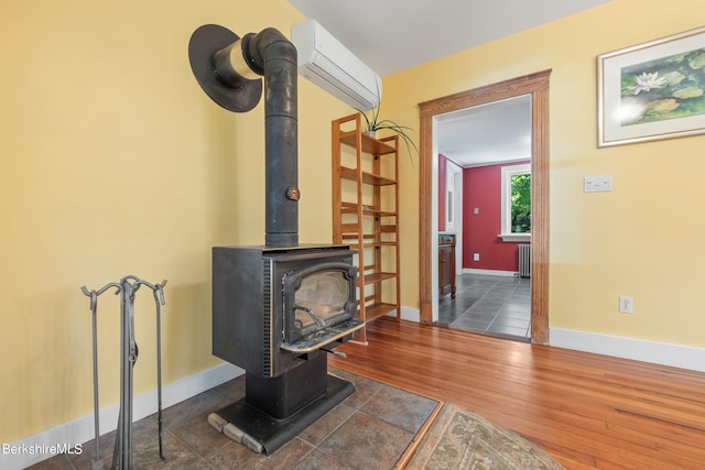 living room with a wall mounted air conditioner, radiator heating unit, a wood stove, and dark wood-type flooring