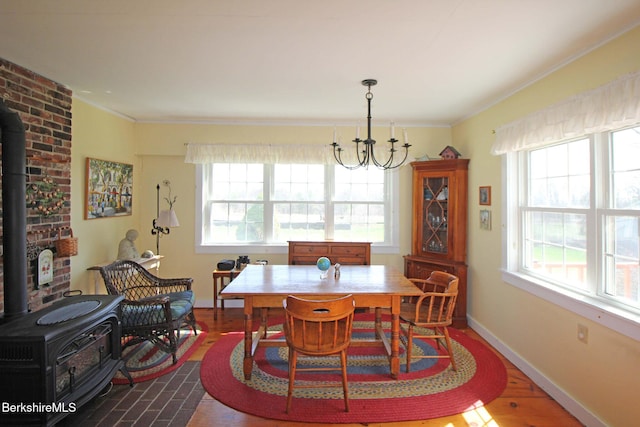 196 Huntington Rd, Worthington, MA 01098 - dining space with a wood stove, plenty of natural light, a chandelier, ornamental molding, and dark wood-style floors