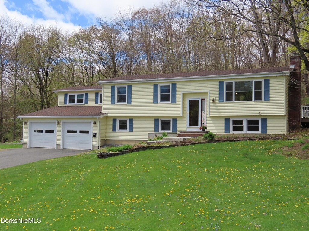 raised ranch featuring a garage, driveway, and a front yard