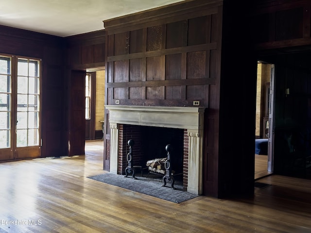 319 Under Mountain Rd, Lenox, MA 01240 - unfurnished living room featuring light wood-style floors, a tiled fireplace, plenty of natural light, and wooden walls