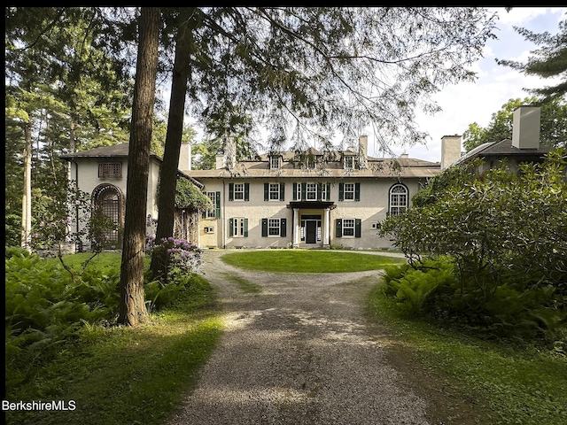 319 Under Mountain Rd, Lenox, MA 01240 - georgian-style home featuring asphalt driveway, stucco siding, a front lawn, and a chimney