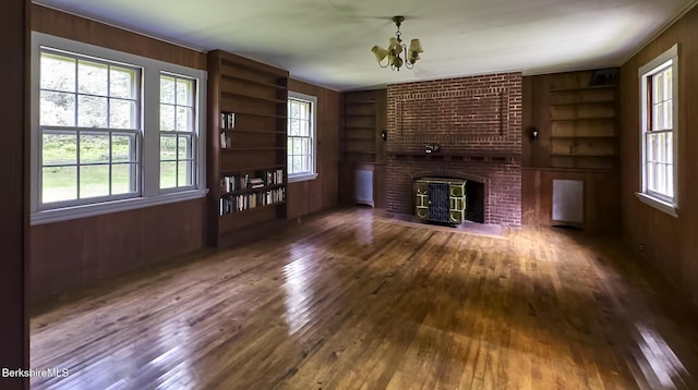 319 Under Mountain Rd, Lenox, MA 01240 - unfurnished living room featuring built in features, a chandelier, hardwood / wood-style flooring, and wooden walls