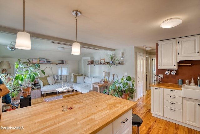 kitchen featuring white cabinets, pendant lighting, and wood counters