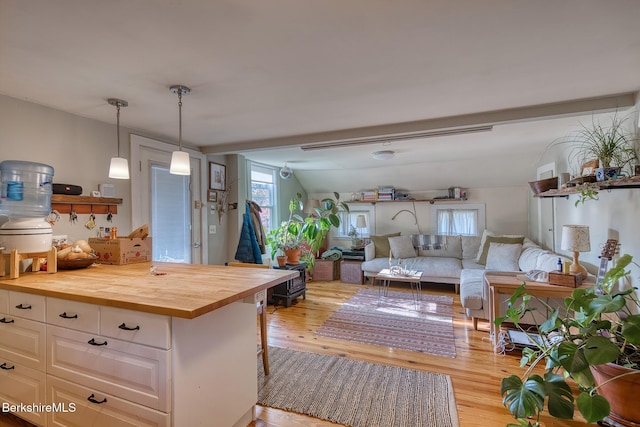 kitchen featuring wood counters, vaulted ceiling, decorative light fixtures, white cabinets, and light hardwood / wood-style floors