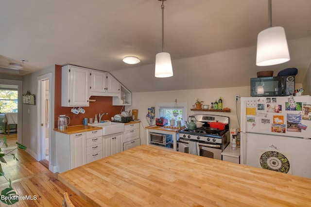 kitchen featuring white cabinets, sink, gas range, decorative light fixtures, and white fridge