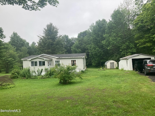 view of yard with a storage shed, a detached garage, a view of trees, and an outbuilding