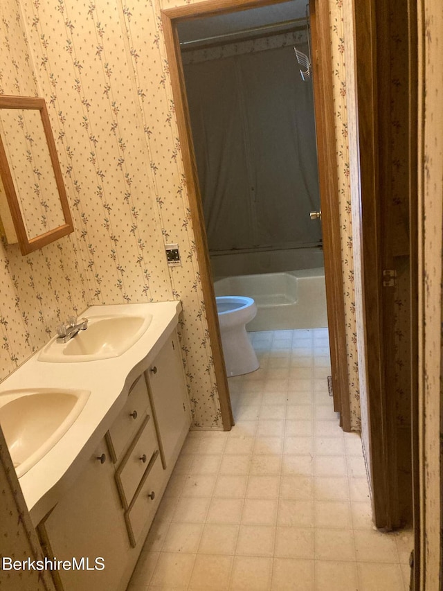 bathroom featuring toilet, wallpapered walls, a sink, and tile patterned floors