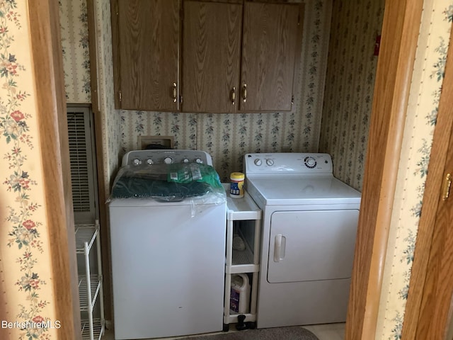 laundry area featuring washer and dryer, cabinet space, and wallpapered walls