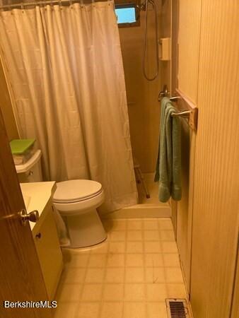 bathroom featuring toilet, visible vents, vanity, a shower stall, and tile patterned floors