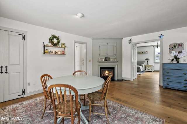 dining area featuring baseboards, wood finished floors, and a glass covered fireplace