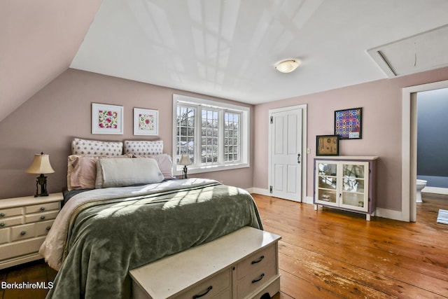 bedroom featuring lofted ceiling, wood-type flooring, attic access, and baseboards