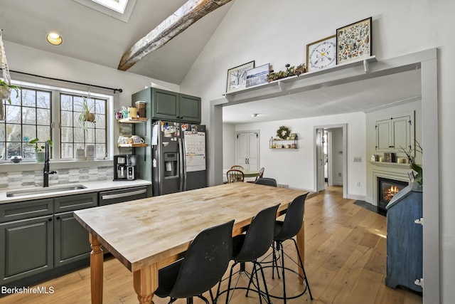 kitchen featuring black dishwasher, a glass covered fireplace, light countertops, stainless steel refrigerator with ice dispenser, and a sink