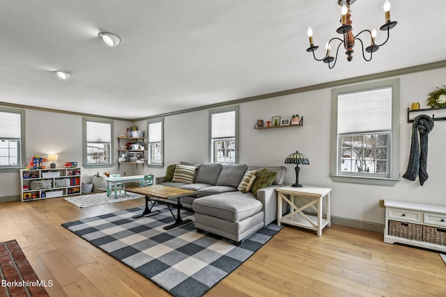 living room featuring light wood-type flooring, a healthy amount of sunlight, crown molding, and an inviting chandelier