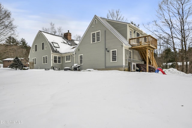 snow covered house with a deck and a chimney