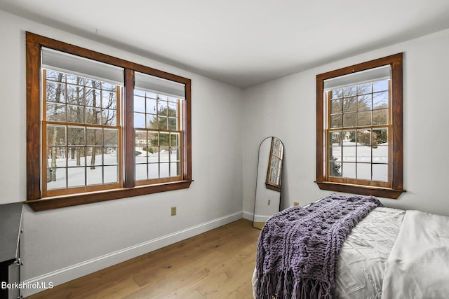 bedroom featuring light wood-style flooring, multiple windows, and baseboards