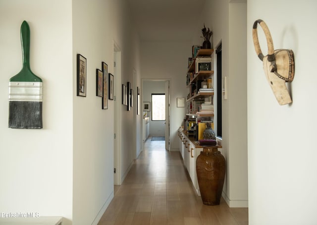 hall with light wood-style floors and baseboards