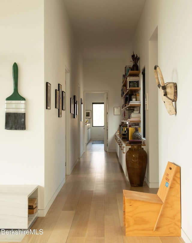 hallway featuring baseboards and wood finished floors