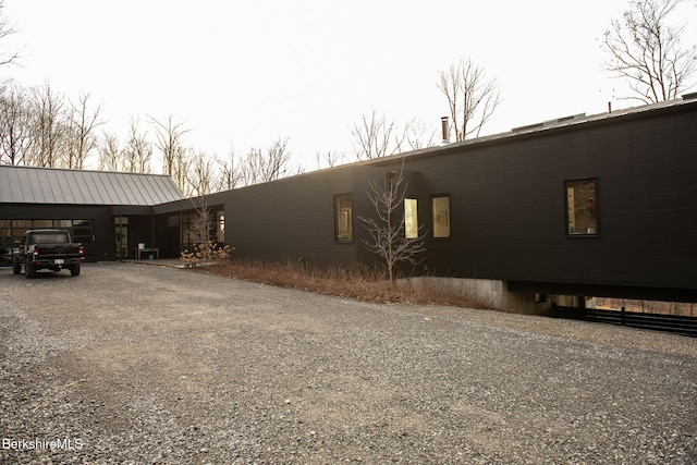 view of side of home featuring metal roof and driveway