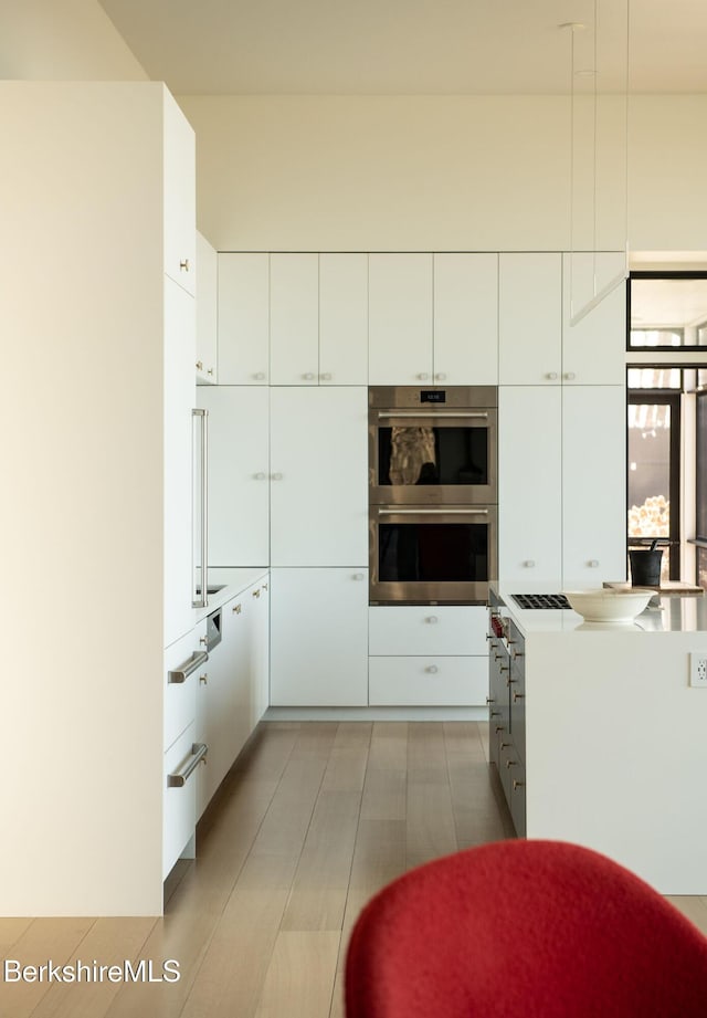 kitchen with stainless steel double oven, modern cabinets, and white cabinetry