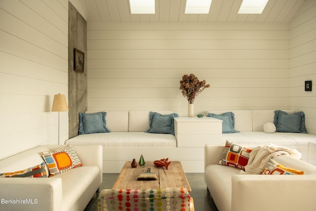 living room featuring a skylight and wood walls