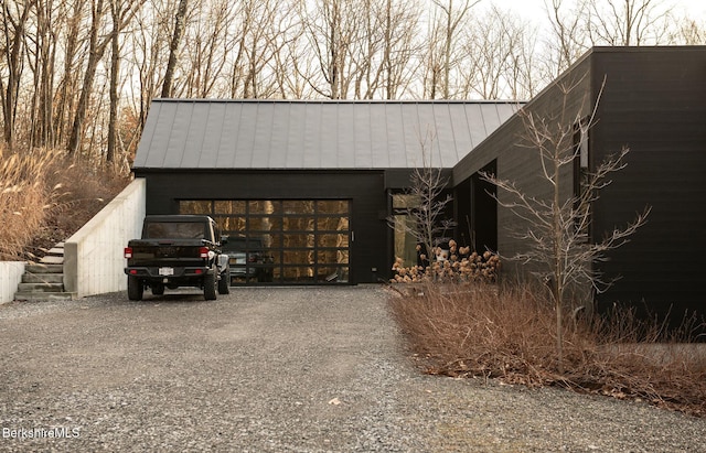 exterior space with gravel driveway, a garage, and metal roof