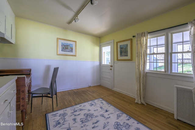 office area with wainscoting, radiator heating unit, a wealth of natural light, and wood finished floors