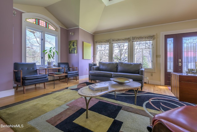 living area with baseboards, a baseboard radiator, light wood-style flooring, and vaulted ceiling