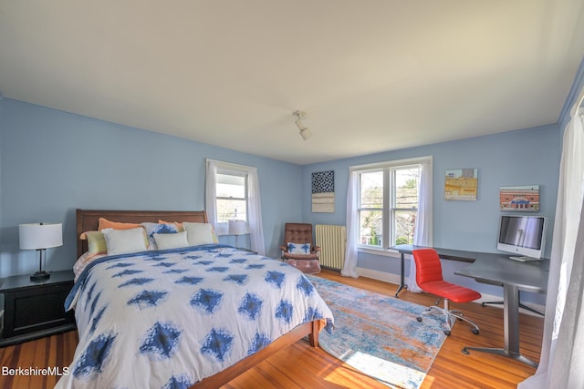 bedroom featuring radiator, baseboards, and wood finished floors