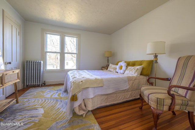 bedroom featuring crown molding, radiator, wood finished floors, and lofted ceiling