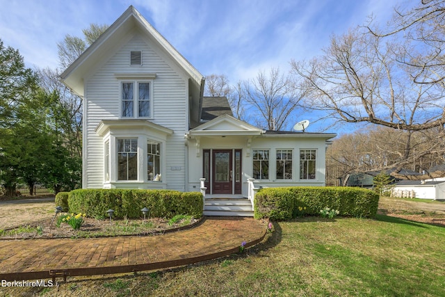 victorian-style house with roof with shingles and a front yard