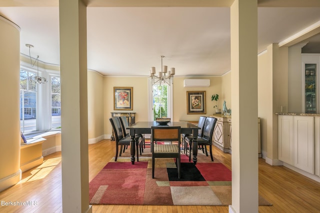 dining area with crown molding, an AC wall unit, light wood-type flooring, and a chandelier