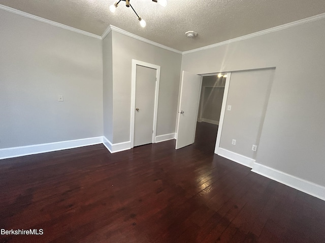 empty room featuring a textured ceiling, baseboards, dark wood finished floors, and crown molding