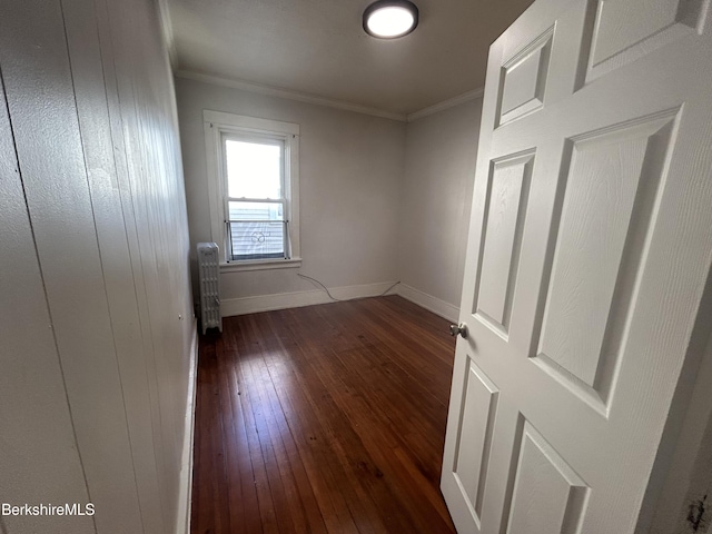 empty room with radiator, dark wood-style floors, baseboards, and ornamental molding