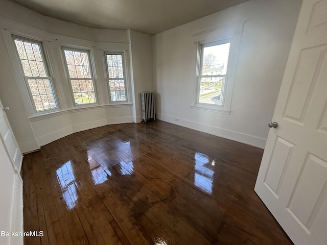 unfurnished room with baseboards, dark wood finished floors, and radiator heating unit