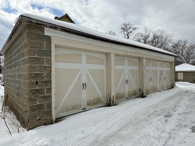 snow covered structure with an outbuilding