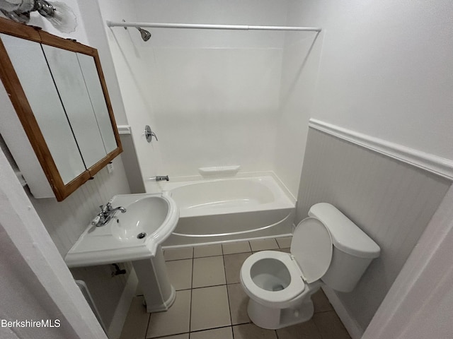 full bathroom featuring toilet, a wainscoted wall, tile patterned floors, washtub / shower combination, and a sink