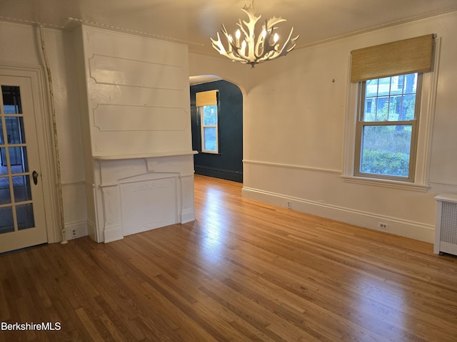 unfurnished dining area with radiator heating unit, a chandelier, and hardwood / wood-style flooring