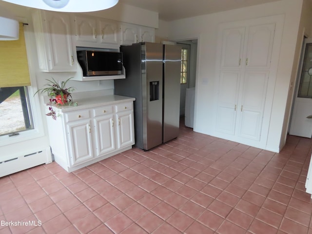 kitchen featuring appliances with stainless steel finishes, light tile patterned floors, white cabinetry, and baseboard heating