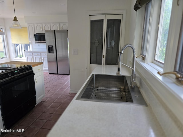 kitchen featuring stainless steel fridge with ice dispenser, black range with electric stovetop, a sink, white cabinetry, and dark tile patterned flooring