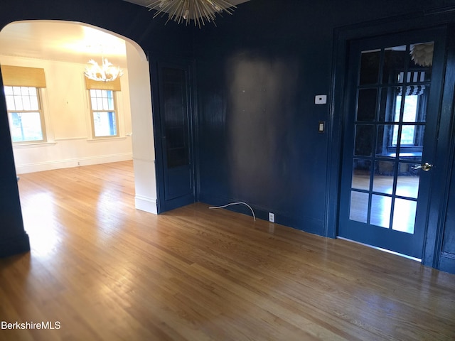 unfurnished room featuring hardwood / wood-style flooring and a notable chandelier