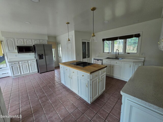 kitchen featuring hanging light fixtures, sink, white cabinets, and stainless steel appliances