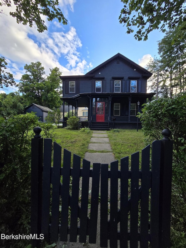 view of front facade with a fenced front yard, covered porch, and a front lawn