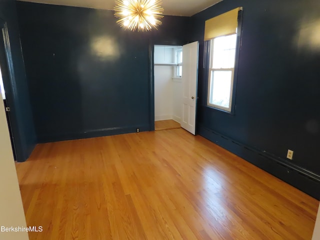 empty room with a chandelier and light hardwood / wood-style floors