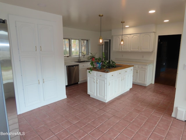 kitchen with appliances with stainless steel finishes, sink, pendant lighting, white cabinetry, and light tile patterned flooring