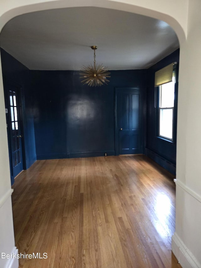 unfurnished dining area featuring hardwood / wood-style floors and a baseboard radiator