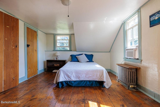 bedroom with dark hardwood / wood-style floors, two closets, radiator heating unit, and lofted ceiling